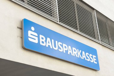 Mavi arkaplan ve havalandırma şebekesine sahip dış bina üzerinde Bausparkasse işareti.