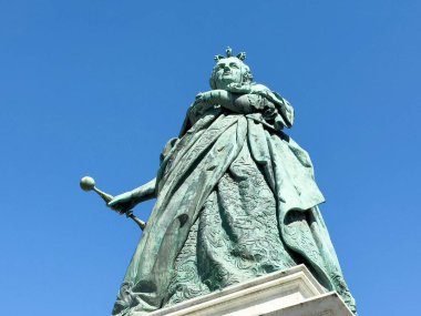 Mavi gökyüzüne karşı heybetli kadın heykeli.