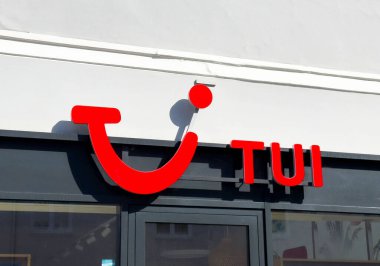 Açık mavi gökyüzü ile dış bina üzerine Tui logosu.