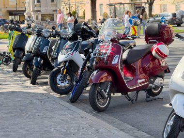 Güneşli bir günde, hareketli scooterları olan bir sokak motosikleti parkı..