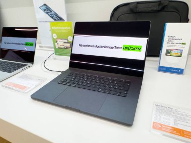 Alman elektronik mağazasında dizüstü bilgisayar ekranında Macbook modelleri sergileniyor..