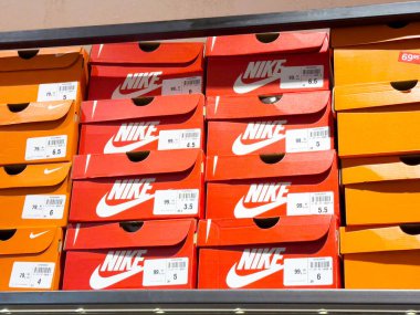 Perakende mağazasında etiketlenmiş Nike ayakkabı kutuları sergileniyor.
