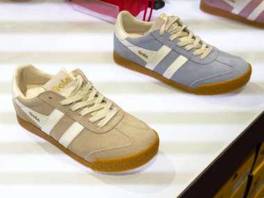 Kahverengi tabanlı ve beyaz çizgili iki klasik spor ayakkabı sergileniyor..