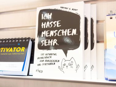 Almanca kitap kapağı konuşma balonu ve çizim ile rafta sergileniyor.
