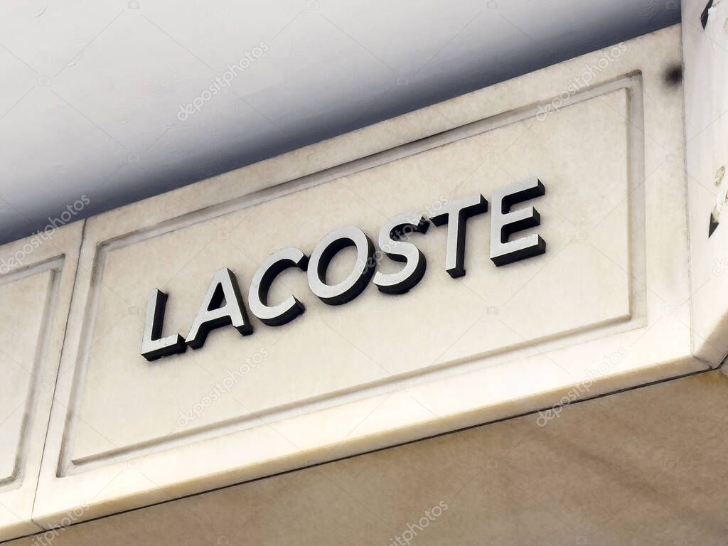 Lacoste storefront signage on beige building wall.
