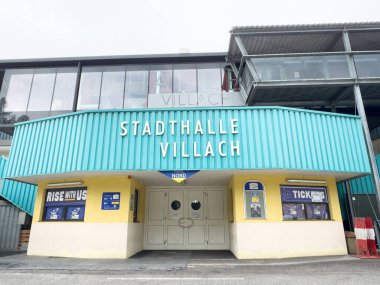 Villach, Avusturya - 17 Nisan 2025: Stadthalle IV Llach binasının dış yüzeyi, modern mimari ve toplumsal etkinlikleri vurgulayan parlak renkler ve tabelalar içeriyor