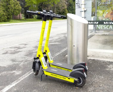 Villach, Avusturya - 17 Nisan 2025: Şehrin bir caddesindeki otobüs durağına park etmiş elektrikli scooter kentsel hareketliliği ve sürdürülebilir ulaşım seçeneklerini ön plana çıkarıyor