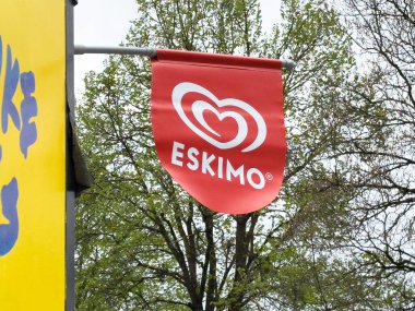 Villach, Avusturya - 17 Nisan 2025: Eskimo dondurma markasının kalp logosunu gösteren kırmızı bayrak canlı bir kentsel çevrede bir dükkanın önünde görülüyor