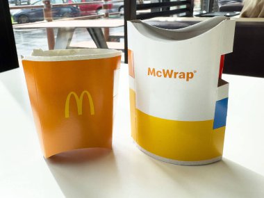 Villach, Avusturya - 17 Nisan 2025: McDonald 's patates kızartması ve McWrap ile fast food ambalajı kolaylığı vurgulayan çağdaş bir kafe ortamında sergilenmektedir