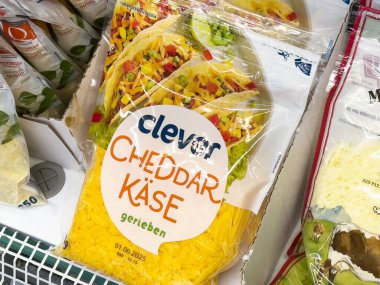 Villach, Avusturya - 17 Nisan 2025: Bir markette çedar peyniri ürün ambalajı canlı renkleri ve mutfak ilhamı için cazip bir tasarımı ön plana çıkarıyor