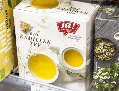 Villach, Avusturya - 17 Nisan 2025: Bitki çayı ambalajı vitrinleri papatya çayı karışımı, doğal malzemeler yoluyla refah ve gevşemeyi vurguluyor