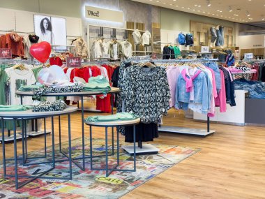 Villach, Avusturya - 17 Nisan 2025: Moda perakende mağazasının iç mekanı modern bir alışveriş deneyimi için canlı giyim sergileri ve şık ürünleri ön plana çıkarıyor