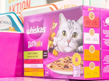Villach, Avusturya - 17 Nisan 2025: Kedi maması ambalajı, lezzetli bir yemeğin tadını çıkaran, evcil hayvanlara yönelik beslenme ve lezzet odaklı neşeli bir kedinin altını çiziyor