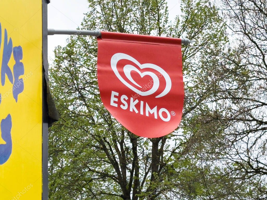 Villach, Austria - April 17, 2025: Red flag displaying heart logo of Eskimo ice cream brand is seen outside a shop in a lively urban environment