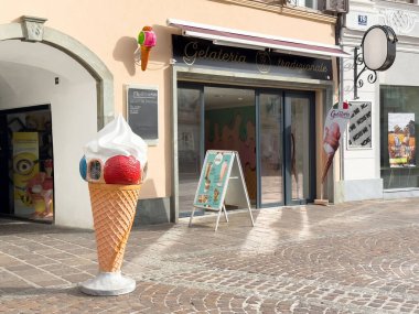 Geleneksel İtalyan Gelateria 'sı, kaldırımlı caddede kocaman dondurma külahları sergileniyor..