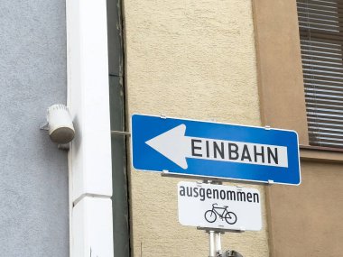 Şehir duvarında bisiklet istisnası olan mavi Einbahn trafik tabelası.