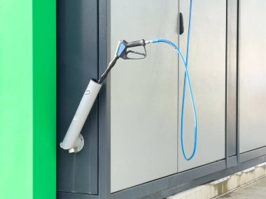 Elektrikli araç şarj istasyonu mavi kabloyla ve dış metale bağlı..