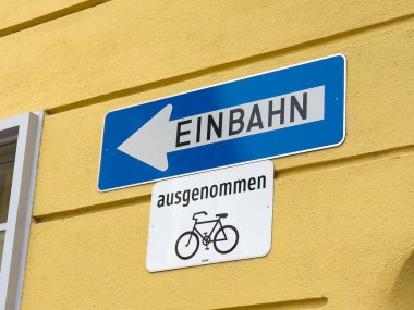 Sarı duvarda bisiklet istisnası olan tek yönlü Alman sokak tabelası.
