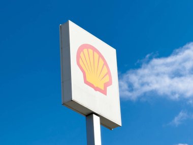 Kabuk logosu bulutlu açık mavi gökyüzüne karşı beyaz işaret üzerine.