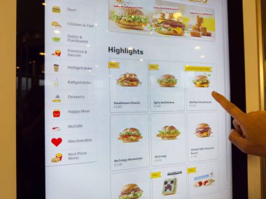Parmak seçme seçenekleriyle birlikte fast food menüsünü gösteren etkileşimli dijital kiosk.