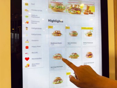 Fast food restoranındaki dokunmatik ekran menüsünde hamburger seçenekleri gösteriliyor..