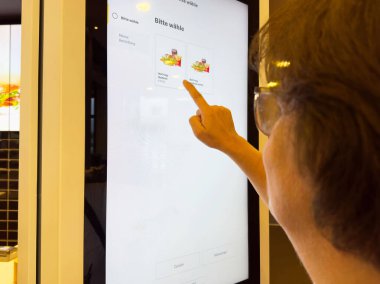 Beyaz tenli yetişkin, fast food 'u self-servis büfe dokunmatik ekranında seçiyor..