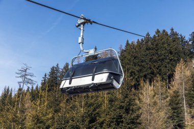 Kayak kaldırma kabini açık gökyüzü ile ormanlık dağın üzerinde asılı..