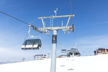 Açık mavi gökyüzü ile karlı dağda kayak merkezi teleferiği.
