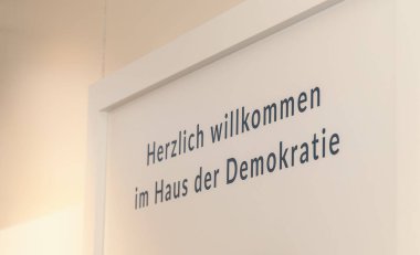 Berlin 'deki Haus der Demokratie' ye hoş geldiniz tabelası. Duvarında Alman metni var..