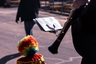 Klarinetist açık hava etkinliğinde renkli bir palyaçoyla performans sergiliyor.