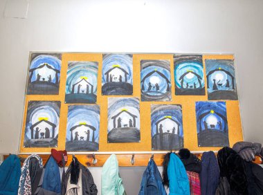 Çocuk kış sanat eserleri ilan panosunda aşağıda ceketlerle sergileniyor..