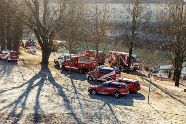 Kışın nehir kıyısında ağaçlarla çevrili acil durum araçları..