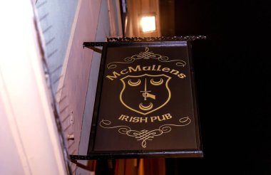 Geceleyin dekoratif tasarım ve sıcak ışıklandırma ile Mcmullens İrlandalı bar tabelası.