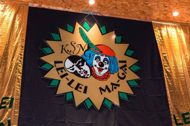 Etkinlikte sahne arkasında palyaço ve maske amblemi.
