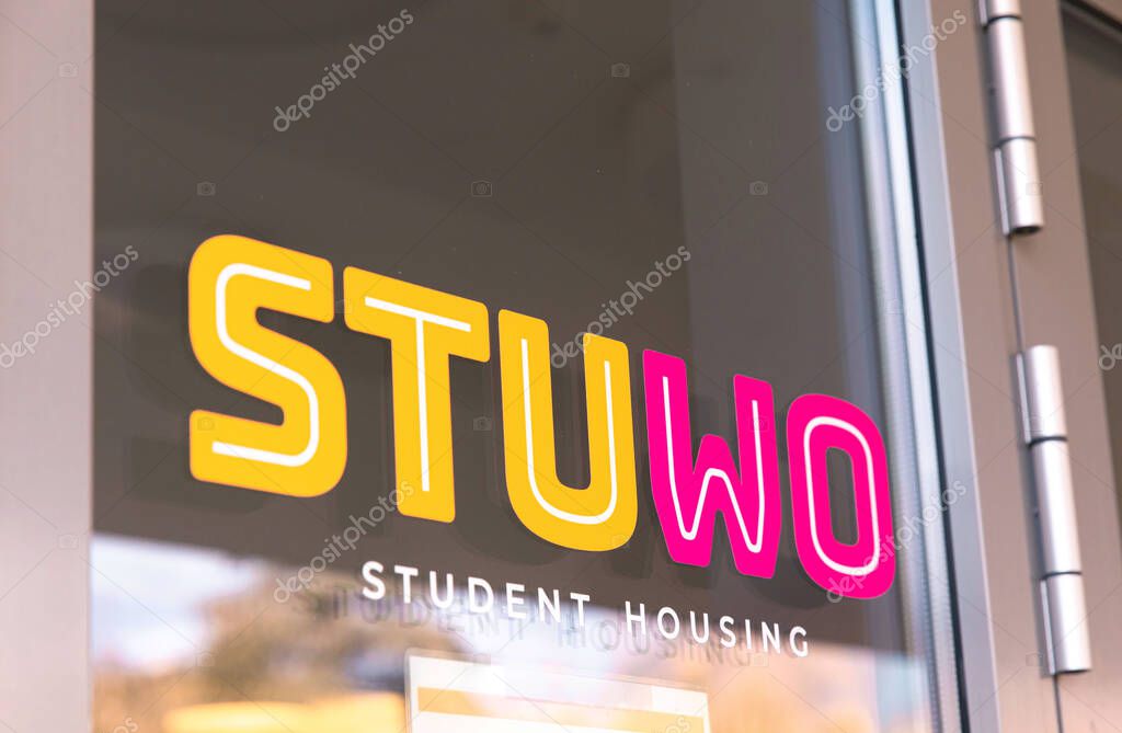Vibrant stuwo student housing sign on glass door reflecting urban environment.