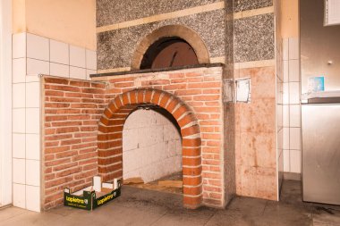 Tuğla pizza fırını, kırsal mutfak ortamında ateş odası açık..