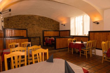 İçi ahşap masalar ve sıcak ışıklandırmalı sandalyelerle dolu, sade bir restoran..