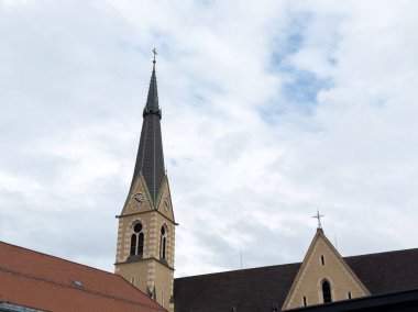 Bulutlu gökyüzüne karşı saat kulesi olan gotik kilise mimarisi.