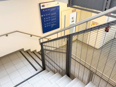 Metal merdiven ve yön işaretli modern ofis içi.