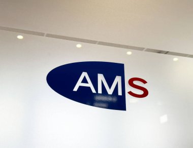 Beyaz duvarda mavi ve kırmızı desenli Ams şirketi logosu.