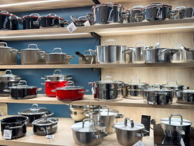 Mutfak gereçleri mağazasındaki raflarda bulunan paslanmaz çelik ve diş mineli tencerelerin çeşitliliği.