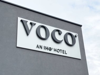 Gri binanın dış tarafında Voco Oteli tabelası.