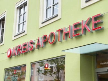 Modern Kreis apotheke cephesinde açık yeşil bina üzerinde kırmızı tabela.