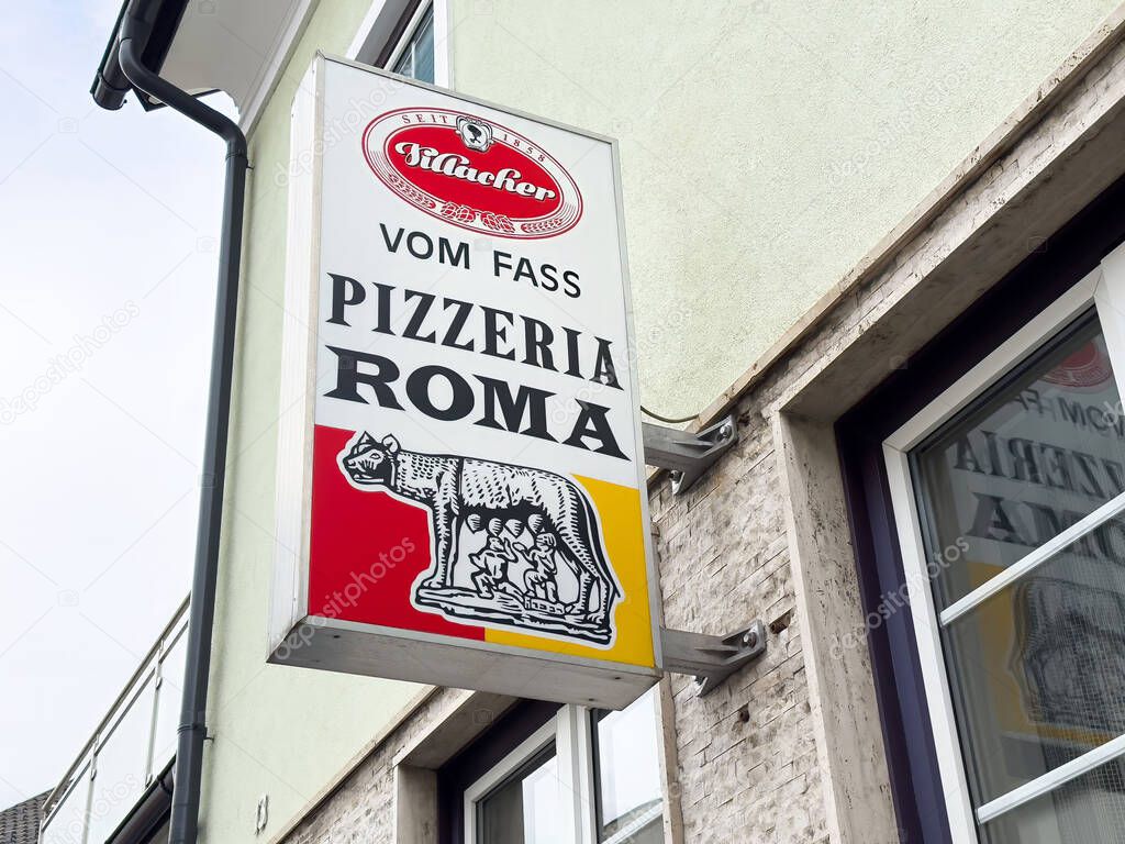 Pizzeria roma sign with italian wolf symbol on building exterior.