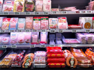 Süpermarket raflarında sosisli ve sosisli sandviç sergilenen paketlenmiş et çeşitleri.