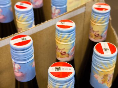 Karton kutuda renkli kapaklı şarap şişelerinin yakın çekimi..