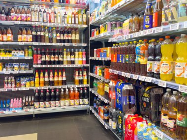 Süpermarkette meyve suları ve meşrubatlarla dolu renkli içecek reyonu.