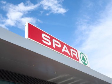 Parlak mavi gökyüzüne karşı spor mağazası logosu.