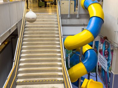 Modern binada merdivenlerin yanında spiral kaydırak olan kapalı oyun alanı.