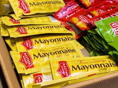 Sergide çeşitli mayonez ve ketçap paketleri var..